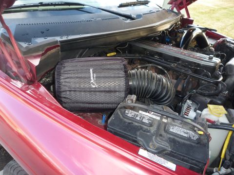 1997 Dodge 2500 - The engine bay of a red 1997 Dodge 2500 features an aftermarket air filter and a visible battery.