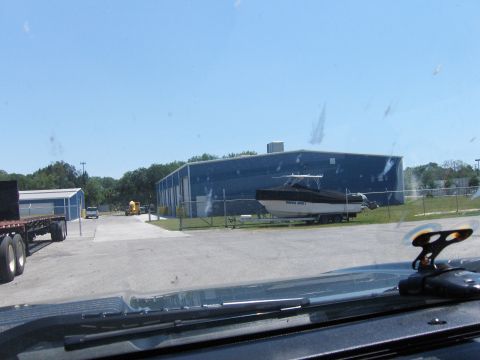 1979 Chevrolet Camaro - A boat on a trailer is parked in front of a large blue building with a clear sky above.