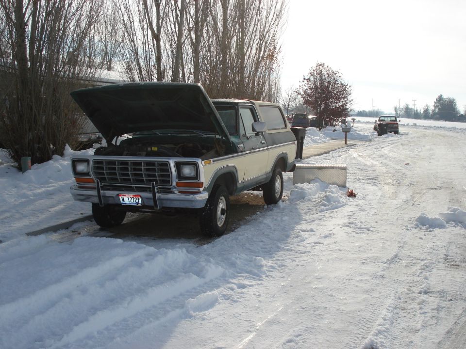 1978 Ford Bronco with hood open in snow. Another truck is visible in the background