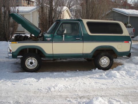 1979 Ford Bronco - This two-tone Ford Bronco is parked outside in a snowy environment with its hood up.