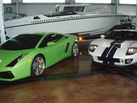 1979 Ford Bronco - A green sports car and a white Ford GT with blue stripes are parked indoors next to a boat.