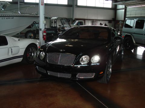 1979 Ford Bronco - A black Bentley Continental GT is parked in a garage with other vehicles.