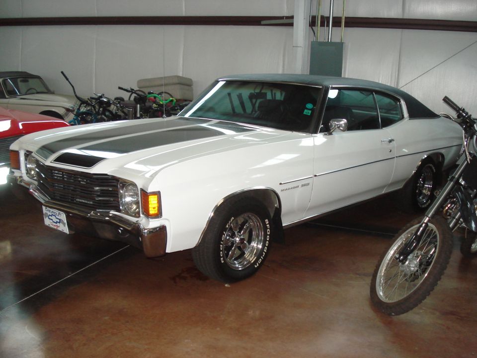 White 1971 Chevrolet Chevelle SS with gray racing stripes, chrome wheels, and a black vinyl roof