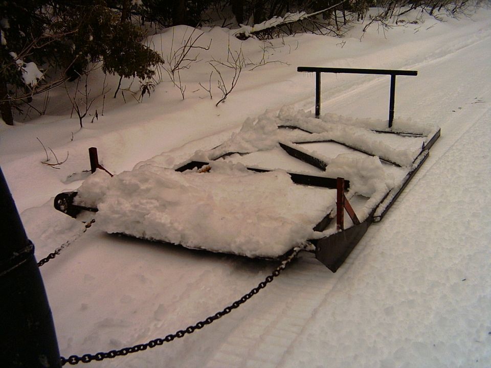 Homemade metal snow drag groomer with chain on snowy trail