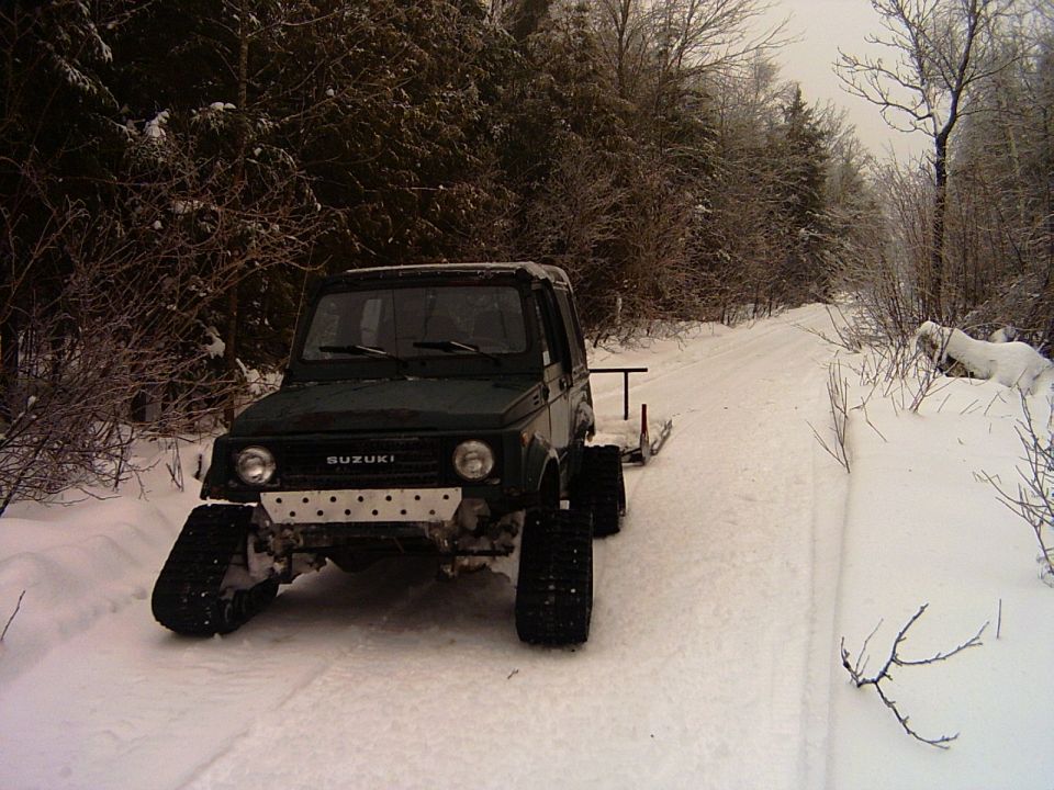 Green Suzuki Samurai on snow tracks parked on a snowy forest trail