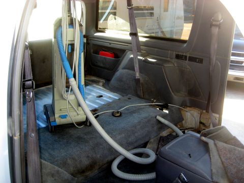 1996 Ford Bronco - Vacuum cleaner inside the rear of a vehicle, with seats removed.