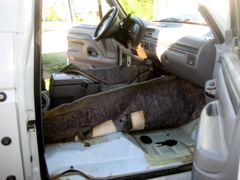 1996 Ford Bronco - The interior of a vehicle is shown with the carpet removed, revealing the floor and parts of the dashboard.