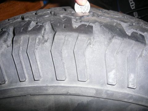 1988 Ford Bronco - Tire tread depth is checked using a coin to gauge wear. The registry claims this is a 1988 Ford Bronco, but the image only shows a tire.