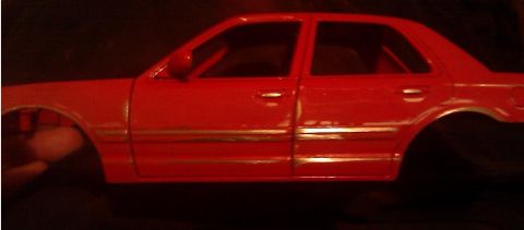 2000 Mercury Grand Marquis - A red car model is shown from the side, with visible doors and chrome trim details.