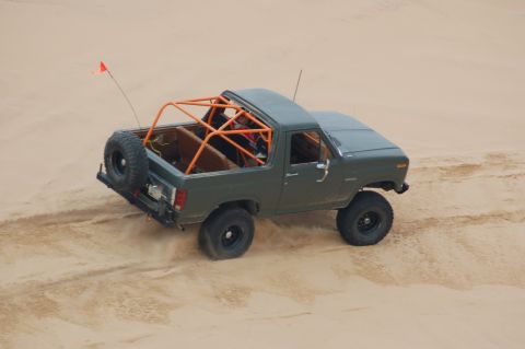 1982 Ford Bronco - This 1982 Ford Bronco is equipped with a roll cage and spare tire, navigating sandy terrain.
