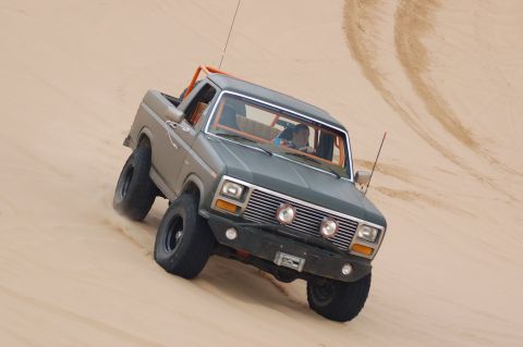 1982 Ford Bronco - This modified Ford Bronco navigates sandy terrain, kicking up dust as it goes.