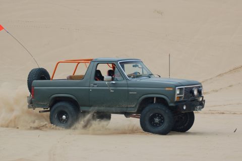 1982 Ford Bronco - This 1982 Ford Bronco is equipped with an aftermarket roll cage and is being driven off-road in a sandy environment.