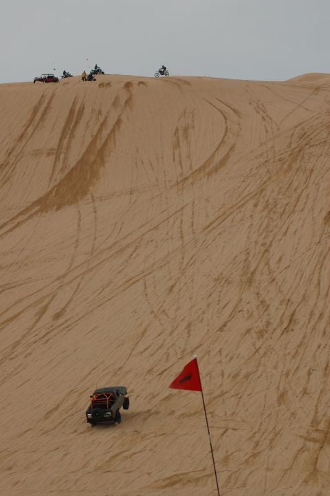 1982 Ford Bronco - Several off-road vehicles are seen on a sand dune, with one buggy descending the slope.