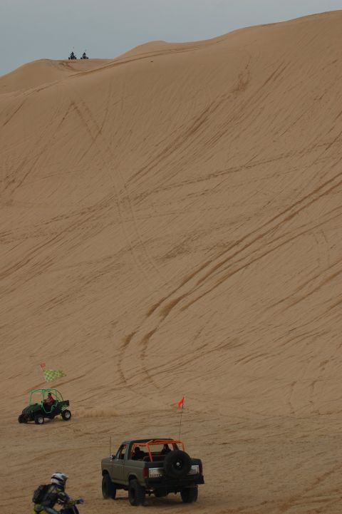 1982 Ford Bronco - A 1982 Ford Bronco and other off-road vehicles navigate sandy terrain under an overcast sky.