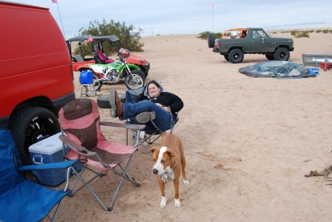 1982 Ford Bronco - A green 1980s SUV with an orange roll cage is parked on the sand, with people and other vehicles nearby.