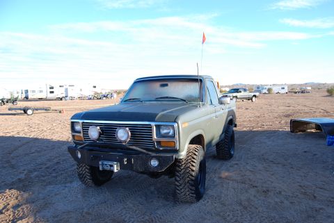 1982 Ford Bronco - This lifted 1980 Ford F-150 pickup truck is parked in a desert area with RVs and other vehicles visible.