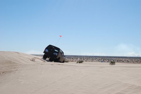 1982 Ford Bronco - A 1982 Ford Bronco navigates a sandy incline under a clear blue sky.
