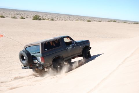 1982 Ford Bronco - This 1982 Ford Bronco is shown navigating sandy terrain, with dust billowing from its tires.