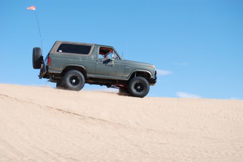 1982 Ford Bronco - This 1982 Ford Bronco is shown off-roading on a sand dune under a clear blue sky.