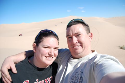 1982 Ford Bronco - A couple enjoys a sunny day at the sand dunes, with a distant ATV hinting at off-road adventures.
