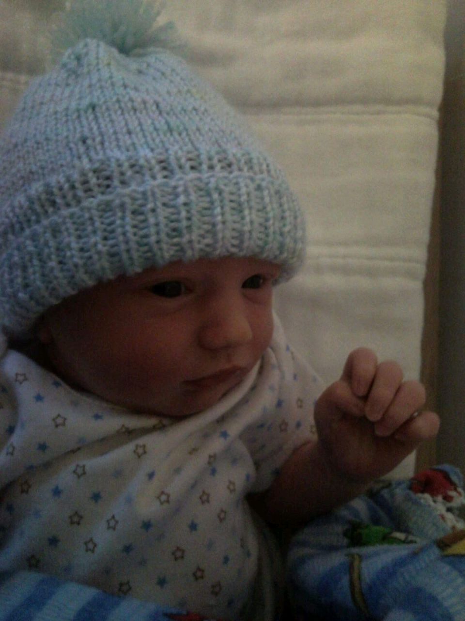 Baby wearing a light blue knitted hat with a pom-pom