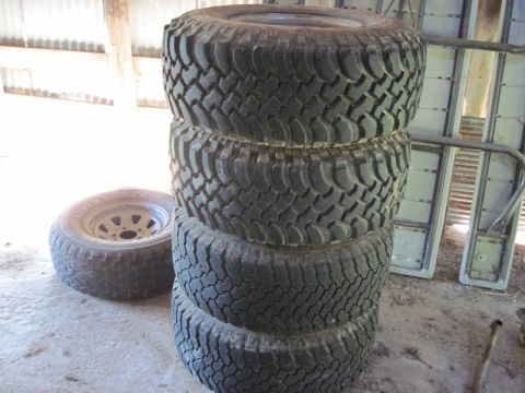 1993 Ford Bronco - A stack of four aggressive tread tires sits next to a single spare tire and wheel.