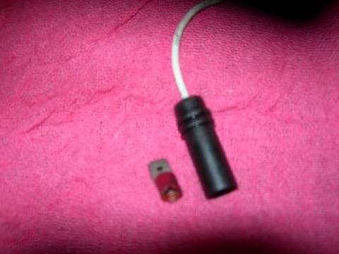 1984 Ford Bronco - A brake pad wear sensor and its connector lie on a pink textured surface.
