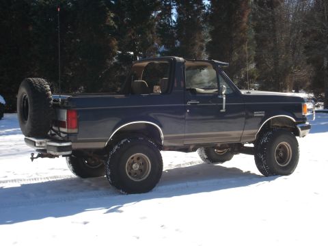 1988 Ford Bronco - This 1988 Ford Bronco features a removable roof and a rear-mounted spare tire, seen here in a snowy outdoor setting.