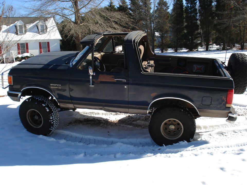 Dark blue lifted full-size Ford Bronco in snow with top removed