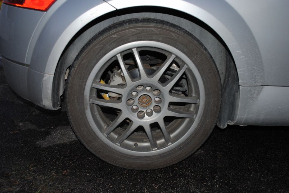 Rear silver alloy wheel with gold center cap and Yokohama tire on silver car