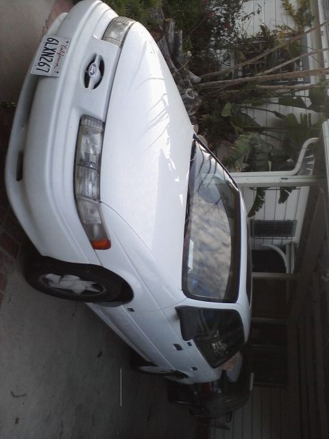 1992 Ford Taurus - A white 1992 Ford Taurus is parked in a residential driveway, showing its front quarter view.