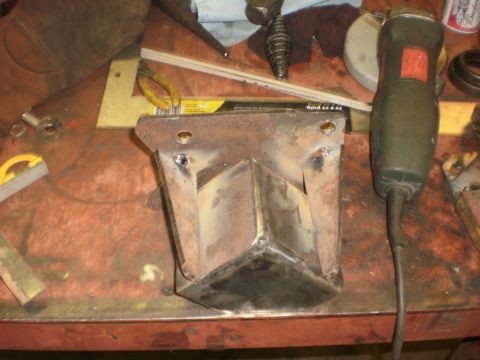 1995 Ford Bronco - A welded metal bracket sits on a workbench, surrounded by tools and materials.