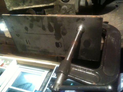 1996 Ford Bronco - A metal plate is secured with a C-clamp and screw to the underside of a vehicle, showing some markings.