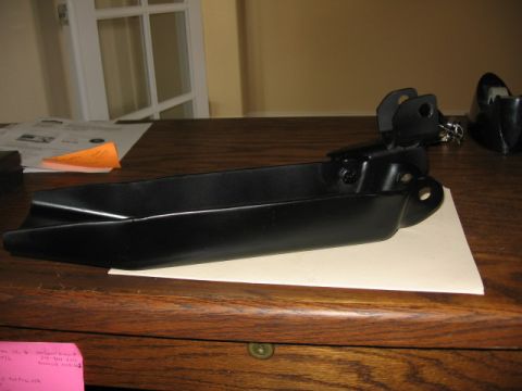 1995 Ford Bronco - Black metal automotive part shown on a wooden desk with papers in the background.