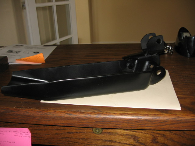 Black-painted suspension arm bracket resting on paper on a wood table