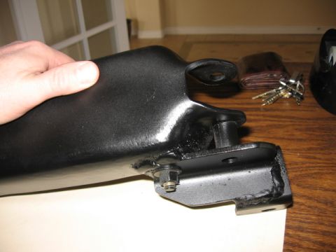 1995 Ford Bronco - A close-up view of a vehicle's suspension component, held by a hand, with personal items in the background.