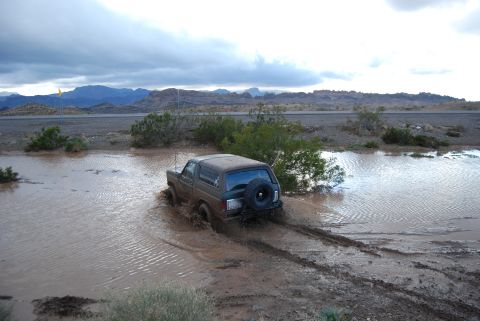 1982 Ford Bronco - This vehicle is navigating through a large mud puddle on an overcast day.