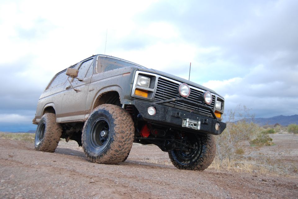 Gray modified SUV with large tires and winch, front 3/4 view