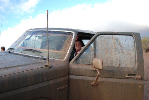 1982 Ford Bronco - Muddy 1982 Ford Bronco with a smiling person in the driver's seat, taken outdoors.