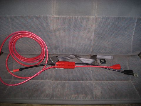 1996 Ford Bronco - Battery cables and fuse holder are placed on a vehicle seat.