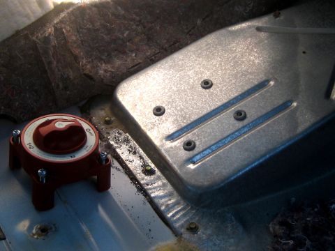 1996 Ford Bronco - A red battery disconnect switch is installed on the floor of a vehicle, near some metal components and insulation.