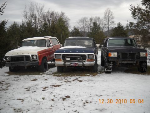 1982 Ford Bronco - Three Ford Broncos from the 1980s are lined up in a snowy outdoor setting with trees in the background.