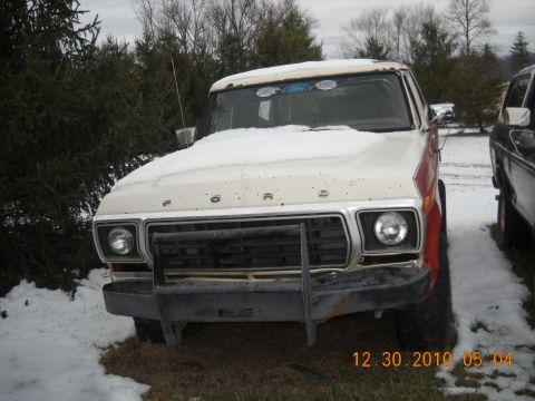 1982 Ford Bronco - This 1979 Ford truck, seen from the front, is covered in snow and features a prominent brush guard.