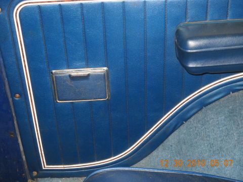 1982 Ford Bronco - Interior door panel detail with blue vinyl and chrome accents, showing a date stamp and website.