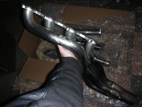 2004 Ford Crown Victoria - Stainless Works exhaust headers being held, with the product logo clearly visible.