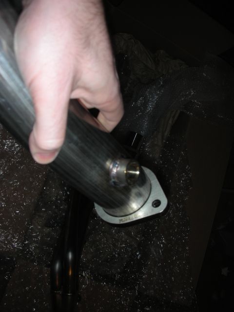 2004 Ford Crown Victoria - A hand holds a stainless steel exhaust pipe component, showing a flange with bolt holes and welding details.