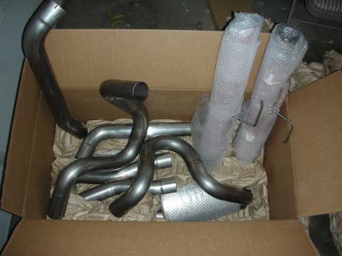 2004 Ford Crown Victoria - New exhaust system parts for a vehicle, including headers and mufflers, packed in a cardboard box.
