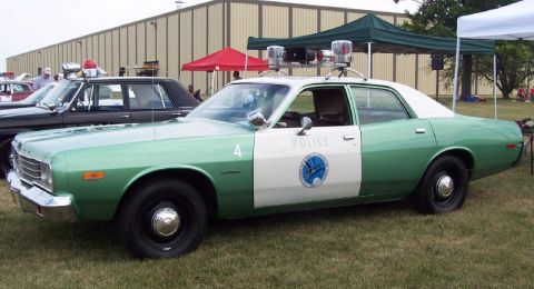 1991 Ford LTD Crown Victoria - Green-and-white mid-1970s Dodge Coronet police sedan displayed on grass at an outdoor show, viewed from the side with unit number 4, "POLIC…