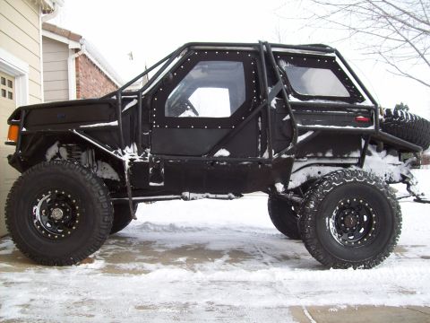 1993 Ford F-150 - This heavily modified vehicle features an extensive roll cage and off-road tires, seen here in a snowy environment.