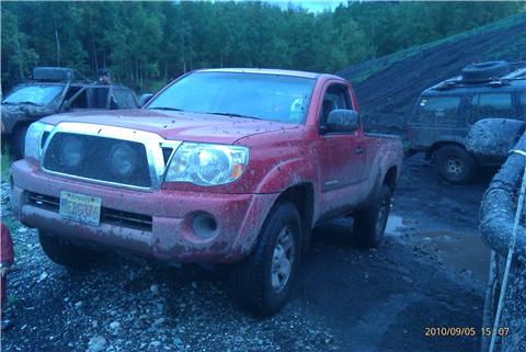 2009 Toyota Tacoma - Red 2009 Toyota Tacoma pickup truck is parked in a muddy area with other vehicles.